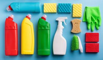 varie bottiglie sanitarie e strumenti per la pulizia su sfondo blu foto