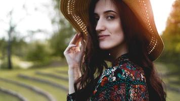 bella giovane donna in splendore attraverso il vestito tocca il cappello di paglia foto