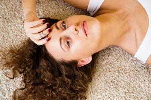 donna sdraiata sul tappeto, felice giovane ragazza adulta sdraiata sul pavimento