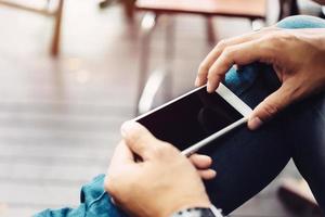 mano dell'uomo d'affari utilizzando il telefono cellulare presso la caffetteria nella luce del mattino foto