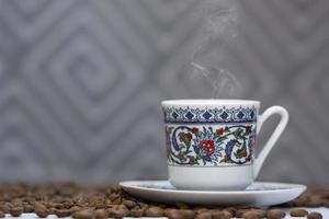 una tazza di caffè turco tra i chicchi di caffè foto