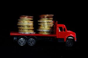 un' rosso camion con pile di monete su superiore foto