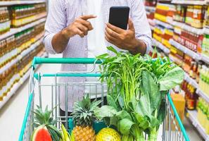 giovane che utilizza smartphone durante lo shopping al supermercato.