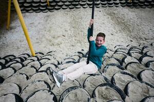 giovane ragazzo avendo divertimento su un' swing a il terreno di gioco. foto