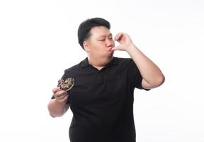 giovane uomo asiatico grasso divertente che mangia ciambelle al cioccolato chocolate foto