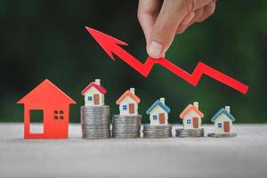 modello di casa e una pila di monete. mercato immobiliare, grafico freccia in su. il concetto di inflazione, crescita economica, investimento immobiliare.