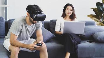 uomo che gioca a un gioco di realtà virtuale mentre la donna lavora da casa foto