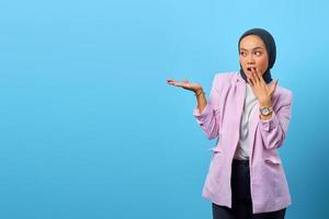 donna asiatica sorpresa che mostra il prodotto su sfondo blu foto