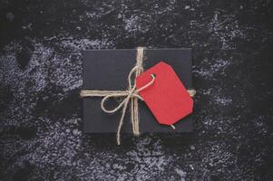 una confezione regalo nera posta su uno sfondo di gesso nero. foto