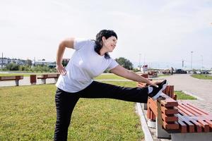 sorridente donna anziana in fase di riscaldamento stretching all'aperto nel parco foto