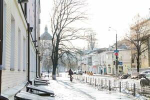 kiev, ucraina-25.12.17 strada dopo nevicata. non cancellato a partire dal il neve brani. ghiaccio su il marciapiede. Visualizza di il Chiesa nel inverno gelate nel kiev su podol. ciclista su il volo a vela coperto di ghiaccio strada. foto