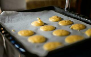 crema pasticciera Impasto delizioso crema soffio torte su cottura al forno vassoio. fabbricazione torte e dolce pasticcini a casa. crema pasticciera torte profiteroles prima collocazione nel forno. foto