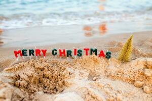 il riva del mare con un' rotolamento onda su il decorato per Natale.. testo a partire dal allegro Natale candelieri foto