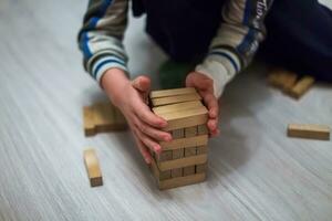 il bambino costruisce un' Torre di di legno blocchi. Torre gioco con un' di legno. legna bloccare impilamento come passo movimento.scala sfocato morbido messa a fuoco foto