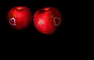 adesivo a forma di cuore su mela rossa su sfondo nero foto