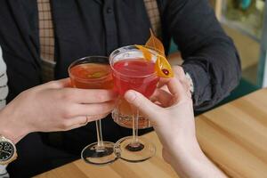 Saluti con alcolizzato cocktail nel mano. un sera con amici nel un' bar foto