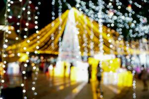 sfocato e bokeh di Natale vacanza illuminazione con persone su notte tempo sfondo. foto