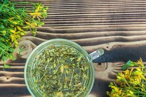 iperico - st johns mosto impianti giallo fiore Usato nel alternativa medicinale. erbaceo tè nel trasparente tazza. utile omeopatico elisir su di legno tavolo foto