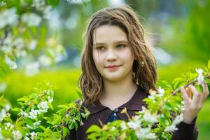 bellissimo ragazza tra ciliegia fiori nel primavera. ritratto di un' ragazza con Marrone capelli e verde occhi. foto