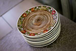 pila di ceramica piatti con dipinto fiori siamo su il tavolo foto