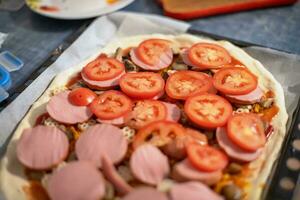 fatti in casa Pizza con salsiccia e fresco pomodori. preparazione cibo a casa a partire dal semplice Alimenti. foto