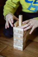 il bambino costruisce un' Torre di di legno blocchi. morbido messa a fuoco foto