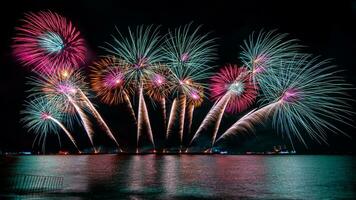 incredibile bellissimo spettacolo pirotecnico colorato nella notte di celebrazione, che mostra sulla spiaggia del mare con multi colore di riflessione sull'acqua foto