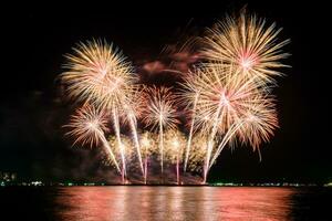 incredibile bellissimo spettacolo pirotecnico colorato nella notte di celebrazione, che mostra sulla spiaggia del mare con multi colore di riflessione sull'acqua foto