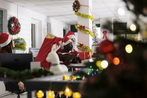 Santa Claus sorprendente africano americano lavoratore a partire dal dietro a nel festivo decorato ufficio. dipendente mascherato nel Natale costume offerta regalo per ignaro collaboratore durante vacanza stagione foto