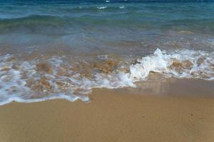 onda schiumosa sulla spiaggia sabbiosa. bella onda sulla spiaggia. foto