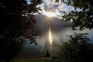 il sole è ambientazione al di sopra di un' lago con alberi foto