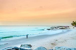 la vista della spiaggia di sabbia e dell'onda del mare con roccia e barriera corallina la mattina? foto
