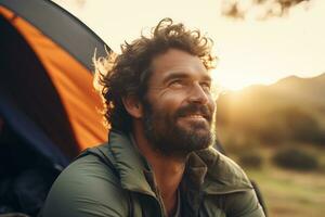 ritratto di uomo guardare a telecamera mentre vicino campeggio tenda a tramonto ai generato foto