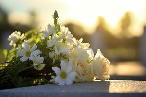 bianca fiori nel davanti di un' pietra sepolcrale a un' cimitero con tramonto.funerale concetto ai generato foto