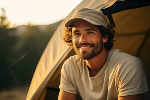 ritratto di uomo guardare a telecamera mentre vicino campeggio tenda a tramonto ai generato foto