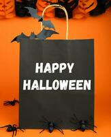 contento Halloween. i regali e shopping per Halloween. vacanza sconti. carta nero Borsa e arredamento per Halloween su arancia sfondo. selettivo messa a fuoco. foto