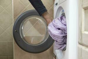 un' uomo mettendo lenzuola nel il lavaggio macchina. casa vita concetto. foto