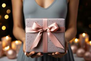 femmina mani Tenere un' regalo scatola con un' rosa arco su un' buio sfondo. donna Tenere regalo scatola su di legno sfondo, avvicinamento. celebrazione concetto. ai generato foto