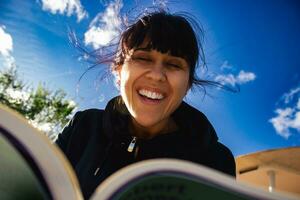 bellissimo inteligente donna lettura un' libro e ridendo. foto