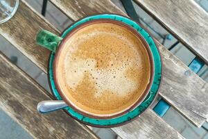 cappuccino nel un' verde decorativo tazza su un' tavolo nel un' bar foto