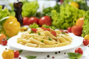 piatto di italiano pasta, penne rigate con pomodori e basilico foto