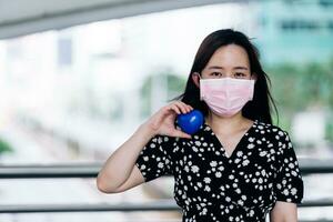 asiatico donna indossare maschera e Tenere blu cuore su mano per proteggere coronavirus o covid-19 concetto. foto