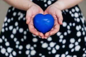 blu cuore nel il mani di un' donna nel un' polka punto vestito foto