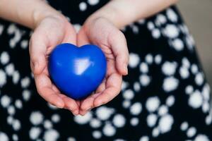 blu cuore nel il mani di un' donna nel un' polka punto vestito foto