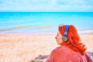 bella donna che ascolta la musica sulla spiaggia foto
