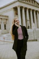 bella donna sorridente che usa il cellulare e cammina foto