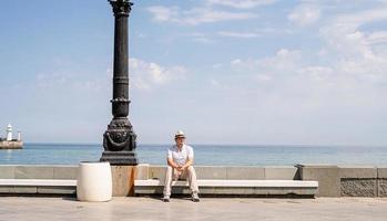 giovane seduto su una panchina in riva al mare foto