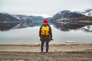 l'uomo in piedi sullo sfondo delle montagne e del lago fa una foto