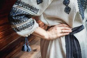 dettagli della camicia ricamata della sposa sullo sfondo di una casa in legno foto