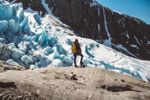 uomo viaggiatore in piedi su una roccia sullo sfondo di un ghiacciaio